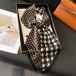 Silk-like scarf with orange check and houndstooth pattern used as a bag accessory