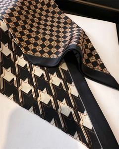 Detail of silk-feel scarves with orange plaid and black geometric houndstooth patterns