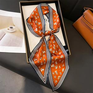 Close-up of orange silk scarf with puppy patterns and striped edges in a gift box