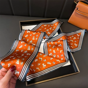 Detail of hand-held orange silk scarf with dog pattern and striped border in gift box