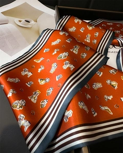 Detail view of silk-like scarf featuring playful dog patterns and striped edges