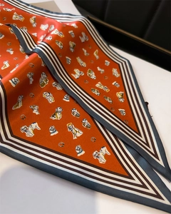 Detail of brick red silk scarf with dog illustrations and striped border patterns