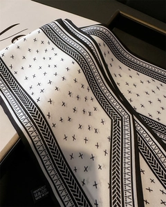 Detail of 100% polyester scarf with black star patterns and care label in gift box