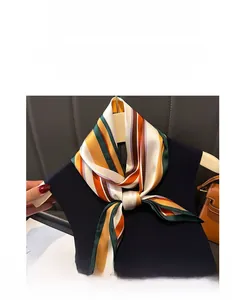 Détail d'un foulard en soie à rayures géométriques colorées noué en cravate fine