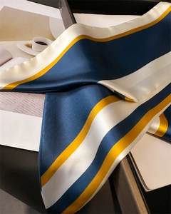 Détail du foulard en satin rayé bleu marine et jaune doré avec une texture soyeuse