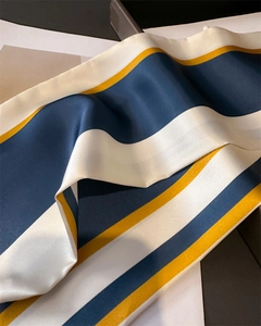Détail du foulard en soie rayé montrant la finition satinée bleu blanc jaune