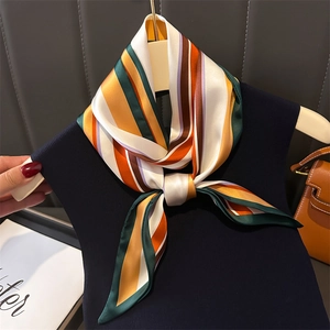Foulard en soie à rayures géométriques orange et vert noué sur un pull en maille bleu marine