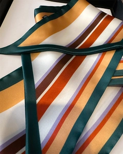 Détail d'un foulard en soie à rayures colorées montrant la texture satinée et l'étiquette