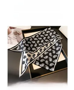 Detail of narrow paisley silk scarf in black and white draped over a gift box