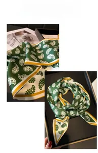 Detail of green paisley silk scarf featuring contrasting borders and smooth texture