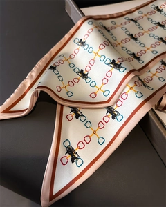 Détail d'un foulard en soie avec motif de chaîne, carrosse et bordure contrastée