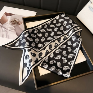 Detail of elegant black and white paisley silk scarf displayed on a luxury leather handbag