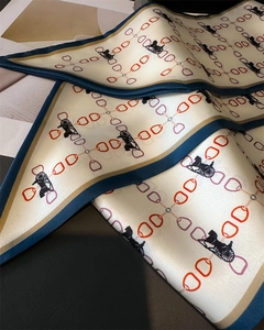 Détail du motif de chaîne élégant sur foulard en soie crème avec bordure marine