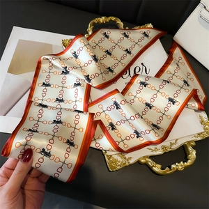 Détail d'un foulard en soie avec imprimé équestre disposé sur un plateau doré