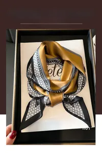 Detail of a silk-feel scarf with yellow and geometric patterns in a luxury gift box