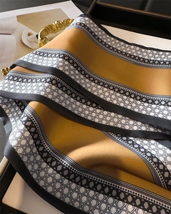 Close-up of silk satin scarf featuring ginger yellow tones and geometric patterns