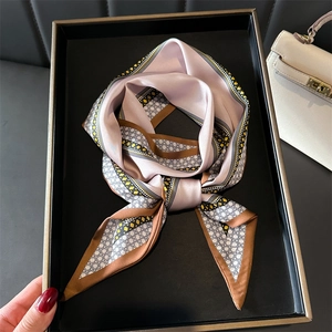 Pink and purple silk-like scarf with geometric patterns on a luxury display tray