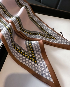 Macro detail of silk scarf showing geometric honeycomb print and smooth fabric texture
