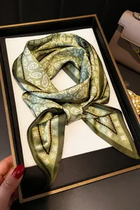 Detail of green paisley silk scarf tied in a bow with elegant geometric patterns