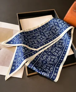 Detail of blue and white paisley silk scarf displayed on a handbag and fashion magazine