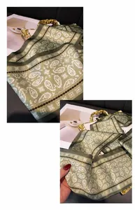 Detail of green paisley silk scarf showing fine texture and neat edge stitching on a tray