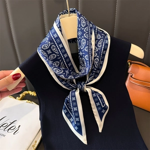 Blue and white paisley silk scarf displayed on a wooden hanger with a classic geometric border