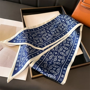 Detail of navy blue paisley silk scarf with white floral border and satin texture