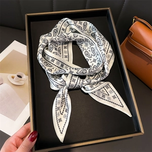 Elegant paisley silk scarf with white and black patterns displayed in a luxury setting