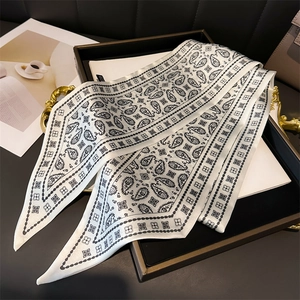 Close-up of black and white paisley skinny scarf in elegant tray for versatile styling