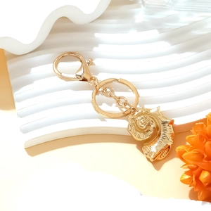 Golden shell pendant keychain with lobster clasp in a stylish ocean-inspired design