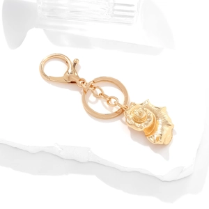 Chic gold seashell keychain with lobster clasp and ring on a minimalist stone base