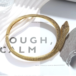 Vintage golden snake-shaped collar necklace with textured scales on a stylish background