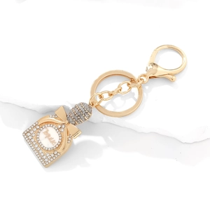 Sparkling crystal tequila bottle keychain with gold bow and rhinestones on white stone
