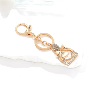 Sparkling gold Tequila bottle keychain with crystals on an elegant white stone plate