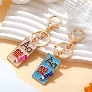 Detail of school themed enamel keychains with blue and pink pendants on white stand