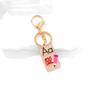 Enamel school book keychain with Aa letters and pencil charm on white marble background
