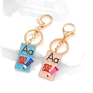 Enamel book keychains with Aa letters and pencil patterns on white stone background