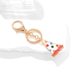 Golden keychain featuring a white birthday hat pendant with colorful polka dots and red tassels