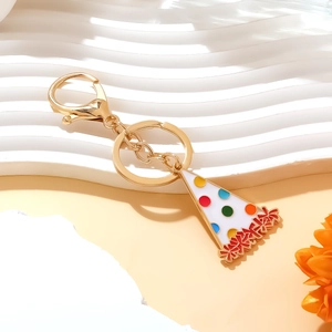 Golden keychain featuring a colorful enamel birthday party hat charm on a white background