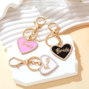 Detail of heart-shaped 'Bride' enamel keychains with pearl trim in pink, black and white