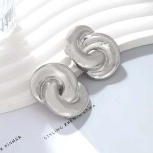 Abstract silver twisted metal hoop earrings with a polished finish and retro design