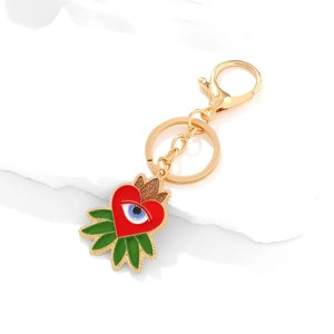 Golden Evil Eye heart keychain with vibrant enamel charms on a white stone pedestal