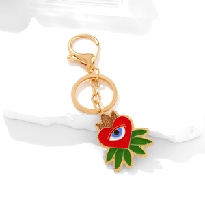 Golden keychain featuring a red heart enamel pendant with a blue evil eye and green leaves