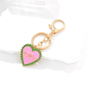Pink and green enamel heart keychain with golden thorn design on stone tray