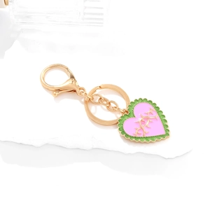 Pink enamel heart keychain with gold branch pattern and lobster clasp on white stone