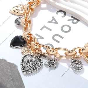 Macro shot of vintage style chunky chain necklace with heart, flower and beetle charms