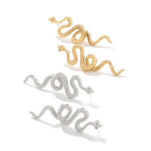 Dettaglio degli orecchini a serpente argento e oro con texture a scaglie e design a curva S