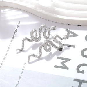 Dettaglio di orecchini a serpente in argento con texture e occhi di zircone
