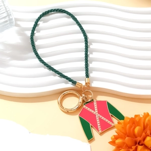 Green braided equestrian keychain with pink enamel horse riding jacket charm on white background