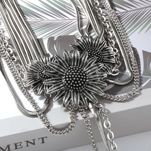 Macro shot of layered silver sunflower pendants with vintage metal chain textures